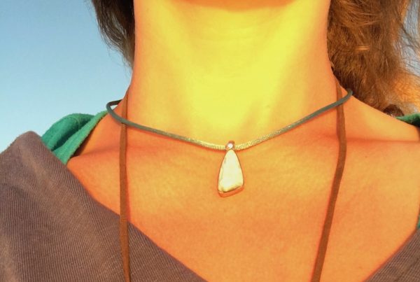 a woman's neck with a necklace on trying to heal a vocal injury