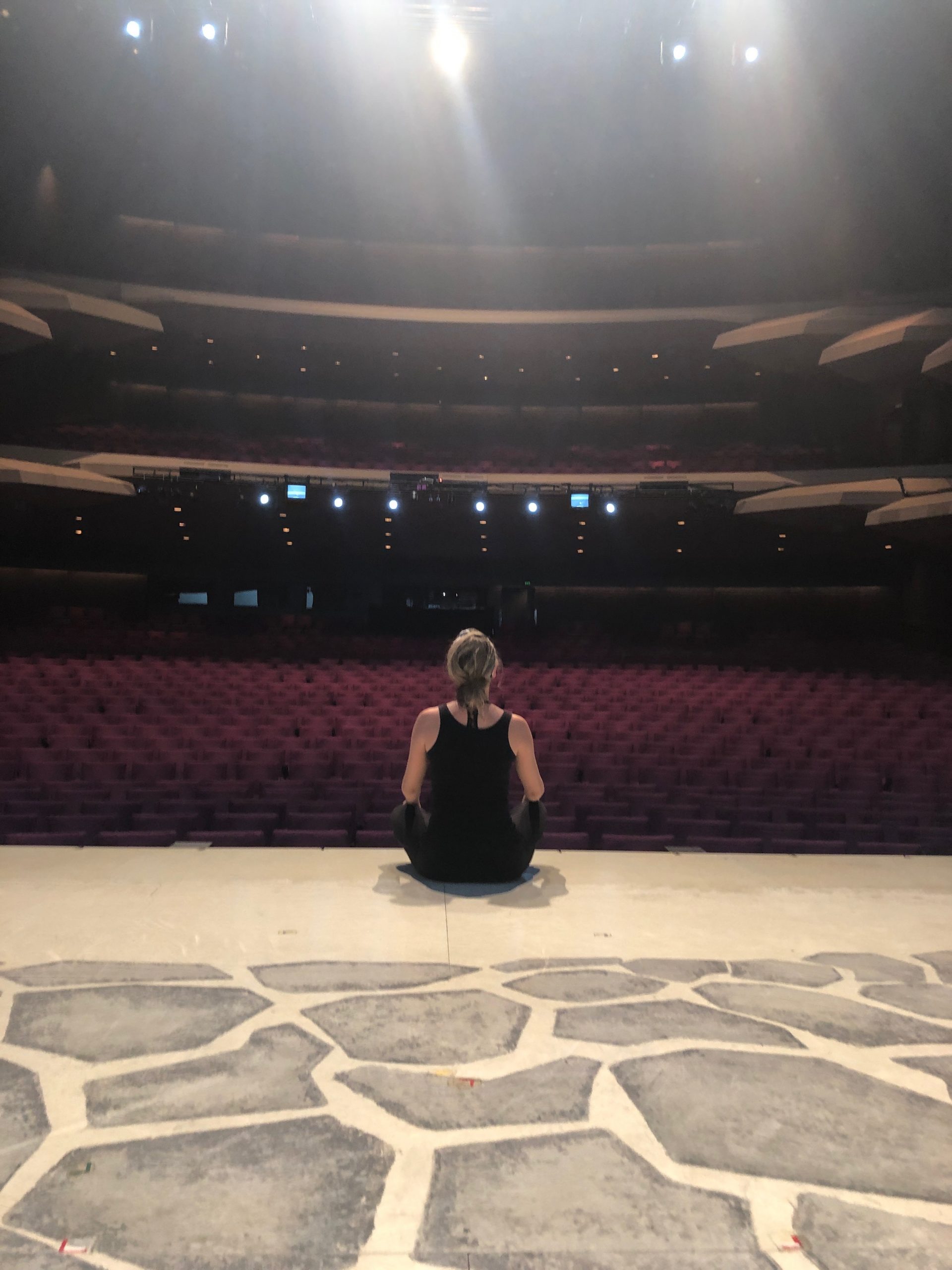 Woman sitting on a stage looking out to the audience