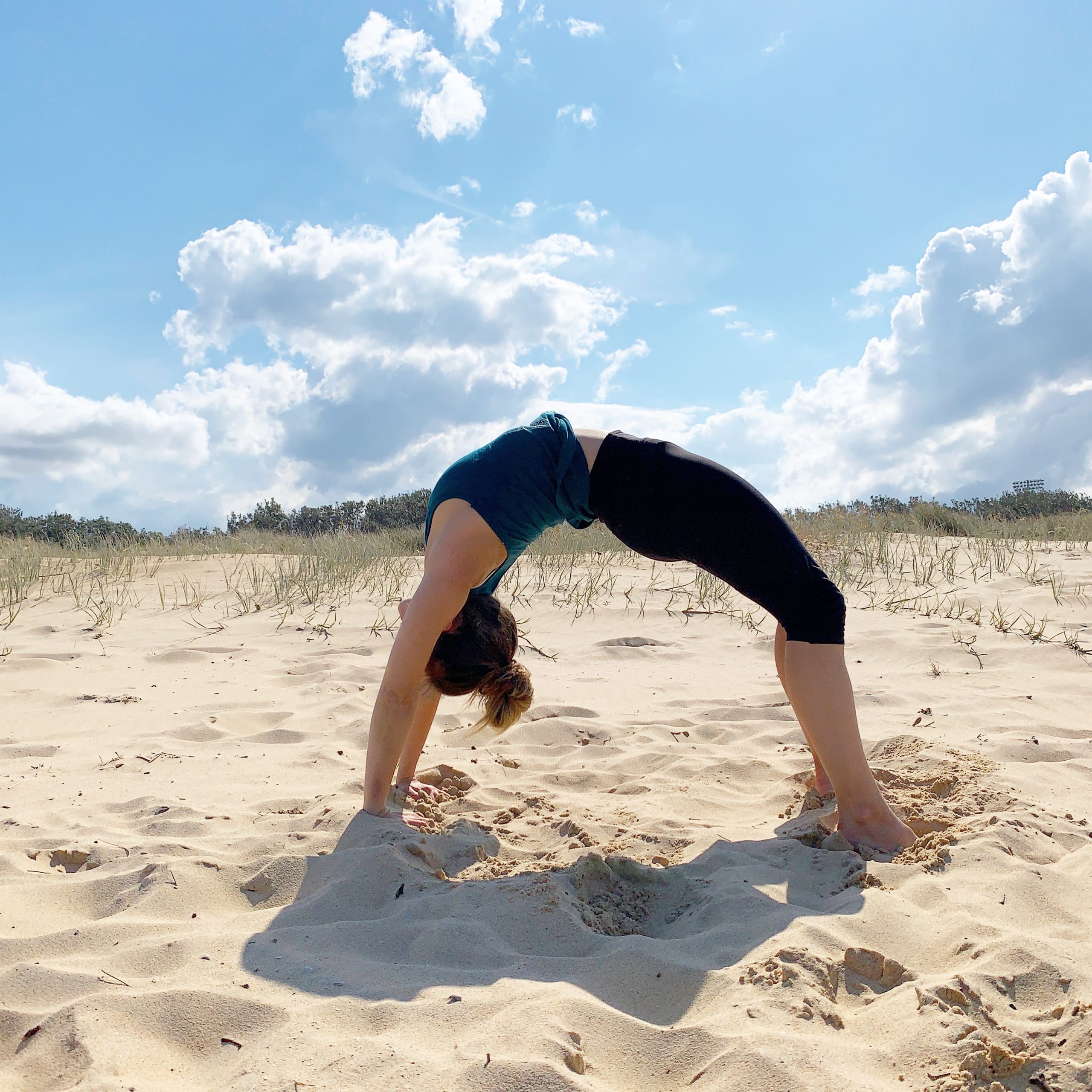 Woman doing Urdhva Dhanurasana Yoga Pose at the beach