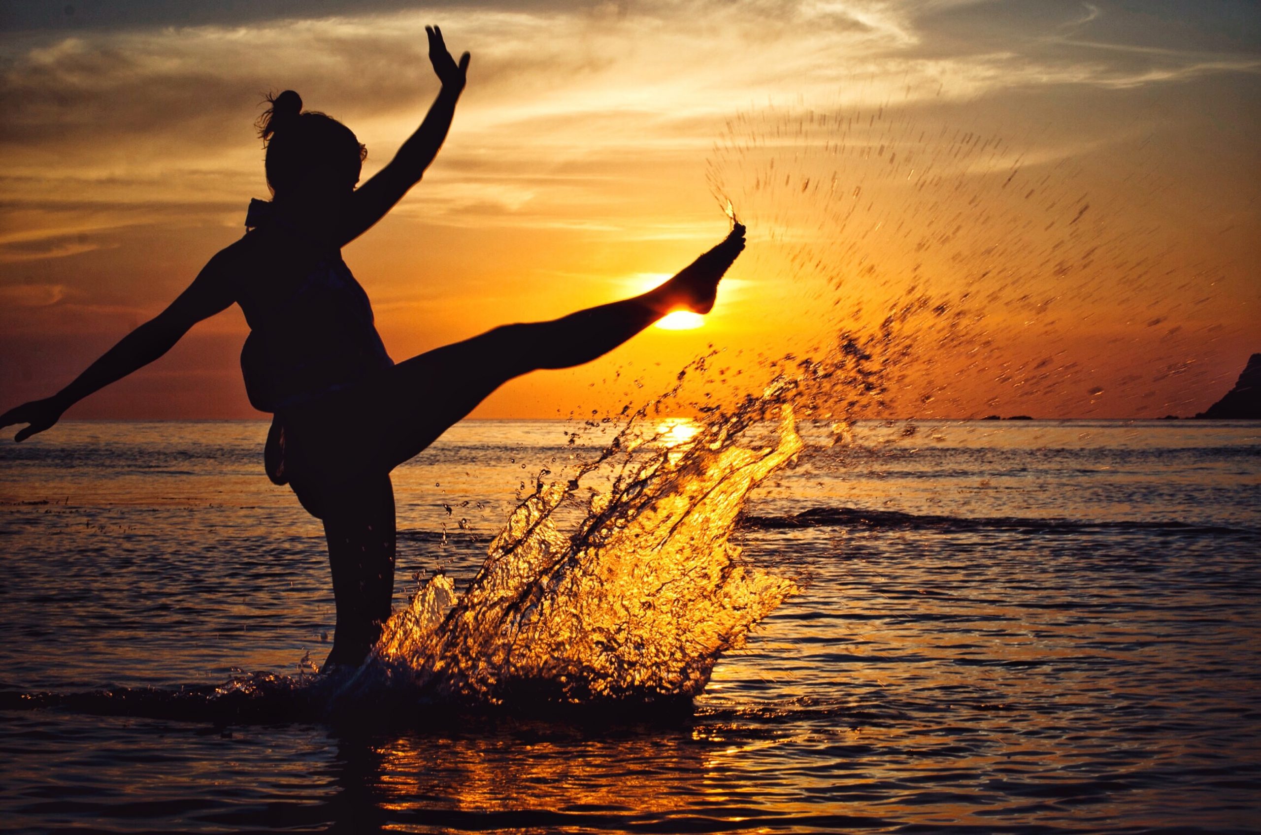 Woman dancing in the sunset at the beach
